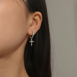 Silver geometric hoop earrings with zircon cross pendant worn by model on ear