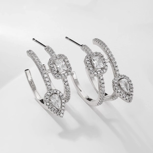 Detailed view of silver drop earrings with emerald cut and pear shaped crystals