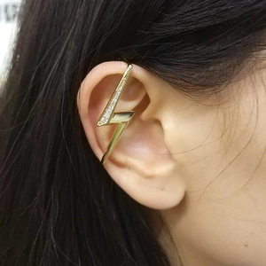 Macro view of a gold lightning bolt ear cuff with white zircon stones on the ear edge