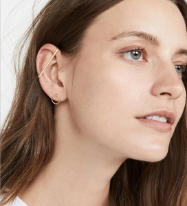 Close-up of minimalist gold plated ear cuff and stud earring with micro-pave cubic zirconia