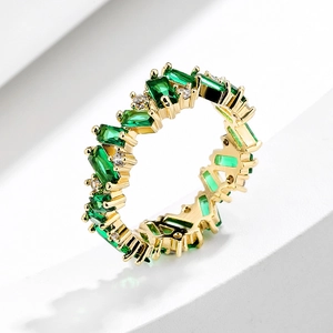 Macro detail of rectangular green zircon stones with white accents on gold plated ring