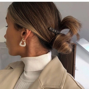 Élégantes boucles d'oreilles créoles dorées avec perles et épingle à cheveux sur un modèle