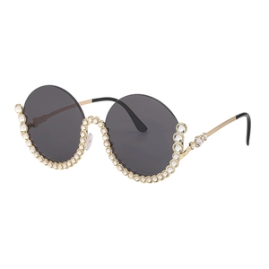 Luxuriöse runde Sonnenbrille mit Strasssteinen und goldenen Metallbügeln im 45-Grad-Winkel