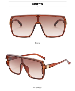 Detail of oversized brown gradient sunglasses featuring golden metal accents on hinges