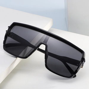 Oversized wrap-around black sunglasses with a modern rectangular frame on white stand