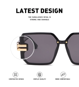 Detail of modern black oversized sunglasses with elegant gold metal hinge and smoke lenses