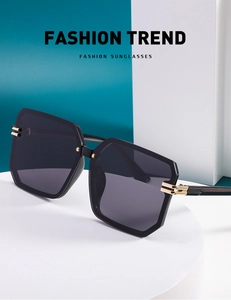 Macro detail of oversized square rimless sunglasses with gold accents on a white stand