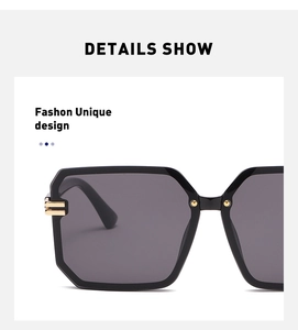 Close-up of geometric square sunglasses featuring black frames and gold metal hinge details