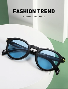 Detail view of round black sunglasses with blue lenses and gold metal accents