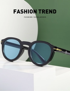 Close-up of retro round black frame sunglasses with blue lenses and gold arrow detail