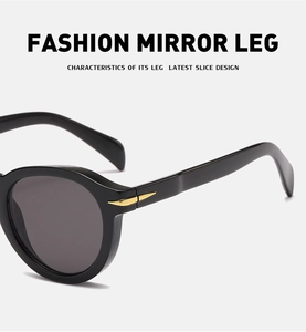 Detail of black retro round sunglasses featuring golden arrow metal hinge on mirror leg