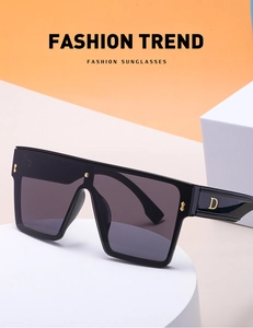Detail of oversized black sunglasses with gold D-letter decor on the temple