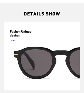 Close-up of black round sunglasses featuring signature gold metal wing hinge accents