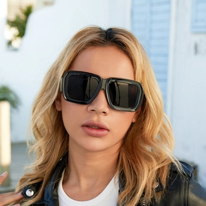 Vue détaillée des lunettes de soleil carrées noires à large monture portées par le modèle