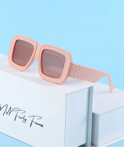 Détail de lunettes de soleil carrées roses avec branches à motif damier sur fond bleu