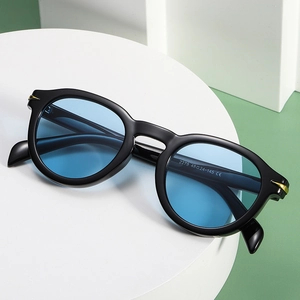 Retro round black sunglasses with blue tinted lenses and gold hinge details on a pedestal