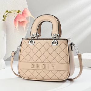 Detail of beige quilted handbag featuring DHGIN embroidery and silver metal hardware