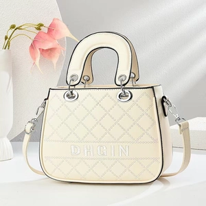 Elegant cream quilted handbag with embroidered logo and silver rings in high-end studio setting