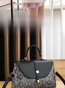 Détail du sac bandoulière imprimé avec boucle dorée sur table en bois et lumière douce