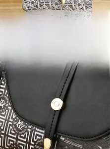 Détail d'un sac bandoulière vintage avec rabat en cuir noir et boucles dorées