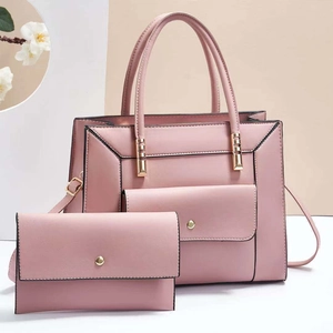Close-up of pink faux leather handbag set with golden metal hardware and black edge paint