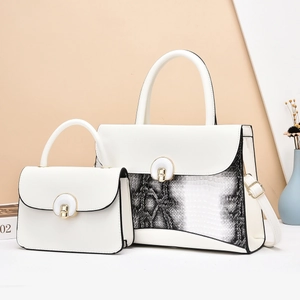 Detail of white leather tote set with snake skin pattern and metal circular lock clasp