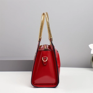 Side view of red patent leather handbag with gold woven handles and metallic finish