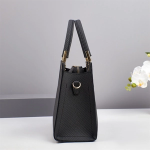 Side view of a black woven texture tote bag featuring elegant gold metal hardware accents