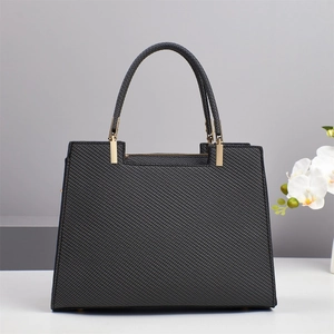 Close-up of black textured crossbody bag with gold hardware and elegant white orchid
