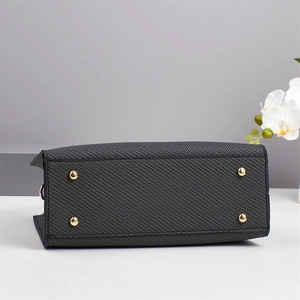 Detail of dark grey handbag base with four gold metal feet on textured leather
