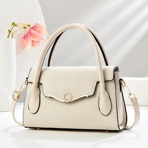 Close-up of beige woven texture handbag with crystal-encrusted gold ring lock detail