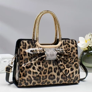 Close-up of leopard print handbag featuring a sparkling rhinestone-studded bow and gold handle