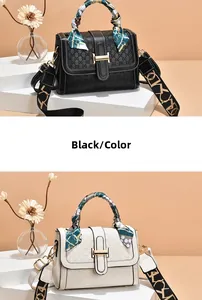 Detail view of contrast embossed handbag with silk scarf handle and H-shaped gold buckle