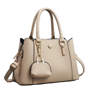 Bolso tote beige con textura de lichi, asas dobles y un mini colgante decorativo