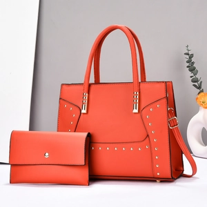 Close-up of orange faux leather tote bag and matching wallet with gold rivet details