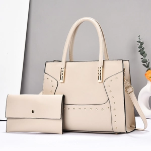 Detail of beige striped tote bag and clutch set with gold rivets and adjustable strap