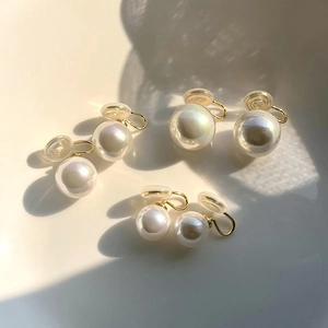 Detailed close-up of natural iridescent pearl clip-on earrings with gold metal accents