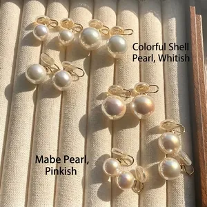Detail of elegant shell pearl clip-on earrings in white and pink hues on jewelry tray