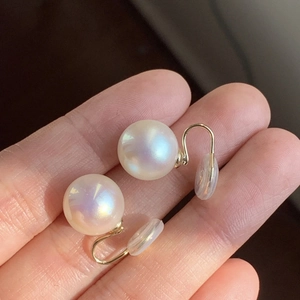 Detail of premium natural pearl earrings with lustrous rainbow sheen and gold hooks