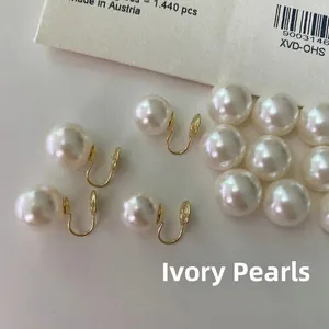 Macro view of creamy white pearls and gold U-shaped clip-on earring for unpierced ears
