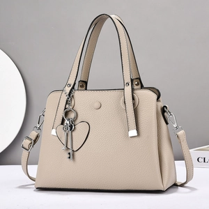 Elegant beige pebbled leather handbag with heart charm and detachable shoulder strap