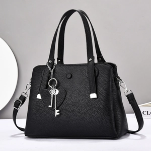 Elegant black lychee leather handbag with dual handles and heart charm accessory