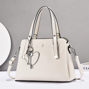 Detailed view of off-white lychee texture leather handbag with heart and key charms