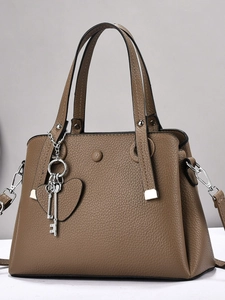 Brown lychee leather tote bag with round buckle and detachable strap in a studio shot