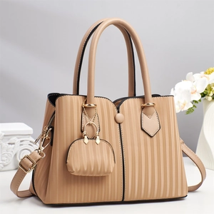 Detail der beigen Tragetasche mit vertikalen Streifen, goldener Mini-Tasche und Schultergurt