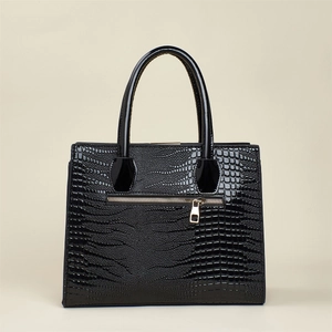 Détail de la texture crocodile noir sur un sac cabas brillant avec des accents dorés