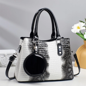 Close-up of white snake pattern handbag with round coin purse charm and black handles
