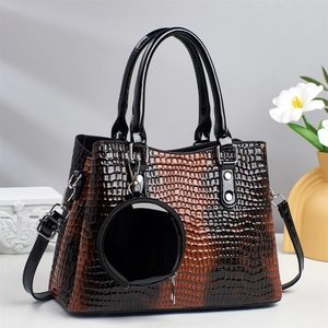 Detail of gradient brown crocodile embossed tote bag with glossy finish and round pendant