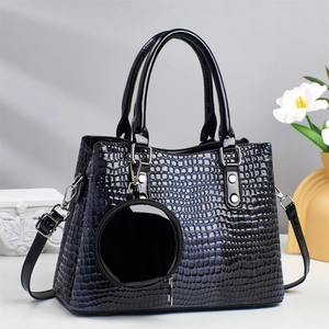 Detail of glossy black crocodile embossed leather handbag with silver metal hardware