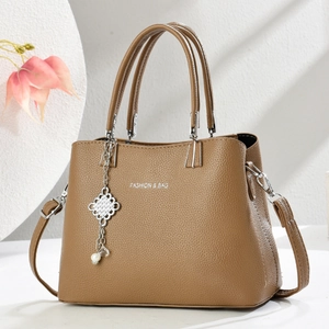 Detail of brown litchi pattern leather bag with pearl metal charm and fashion text